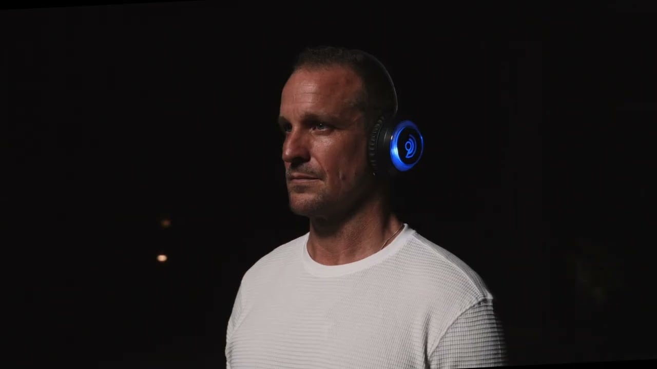Brian Kelly portrait in low light wearing glowing 9D headphones