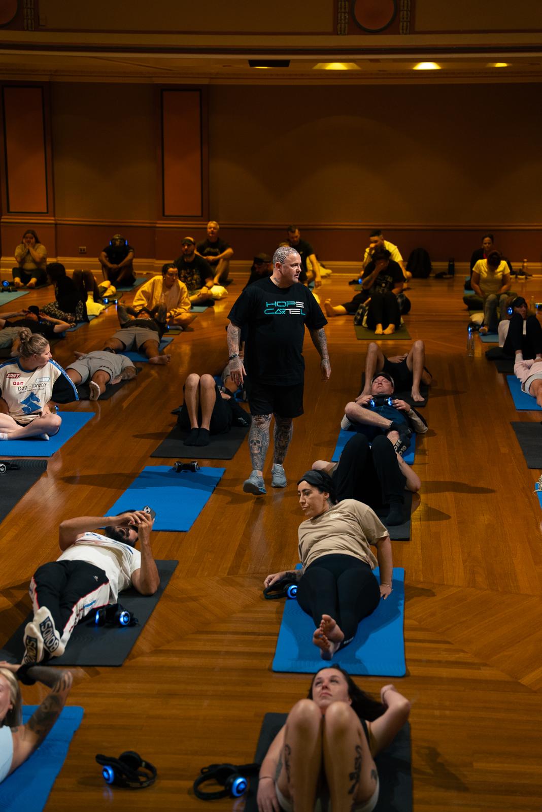 Gaz Wright walking among participants lying on mats at a Hope Cartel breathwork session